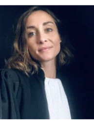 Avocate souriante en tenue professionnelle, fond sombre.